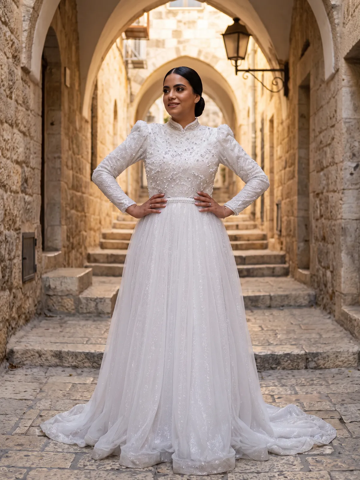 שמלת כלה צנועה עם מחוך תחרה, שרוולים ארוכים וחצאית טול, בסמטת אבן בעיר העתיקה בירושלים